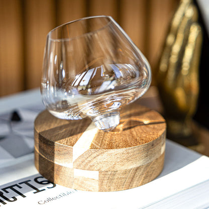 Exposed crystal handcrafted Aequilibrium distillate glass by Audacem on wooden coaster on bookshelf. Rotating design